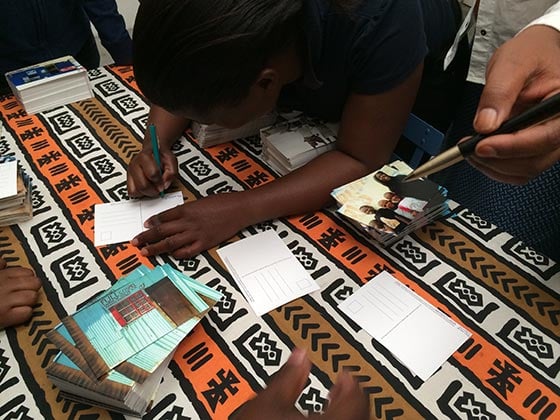 Nwabisa Ndongeni signs postcards as a ‘thank you’ to donors. Photo by Andrea Rees.