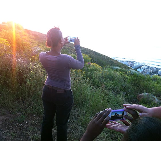 Mobile Photography Empowers Women in South Africa and Fights Poverty 7 Ntombebhongo Pikoli poses as I teach the ladies how to photograph a silhouette on Sunset Hill in Cape Town, South Africa. My hands are pictured with Nwabisa Ndongeni’s hands. Photo by Aviwe Dalingozi.