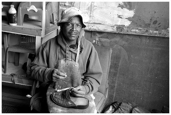 A photograph of a shoe repairman in Khayelitsha, South Africa. Postcard 1.2 by Veliswa Wowo.